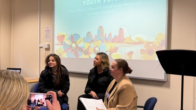 Chair Emma Toby with two Brooklands Technical College students seated at a Youth Voice panel session, with a projected slide behind them