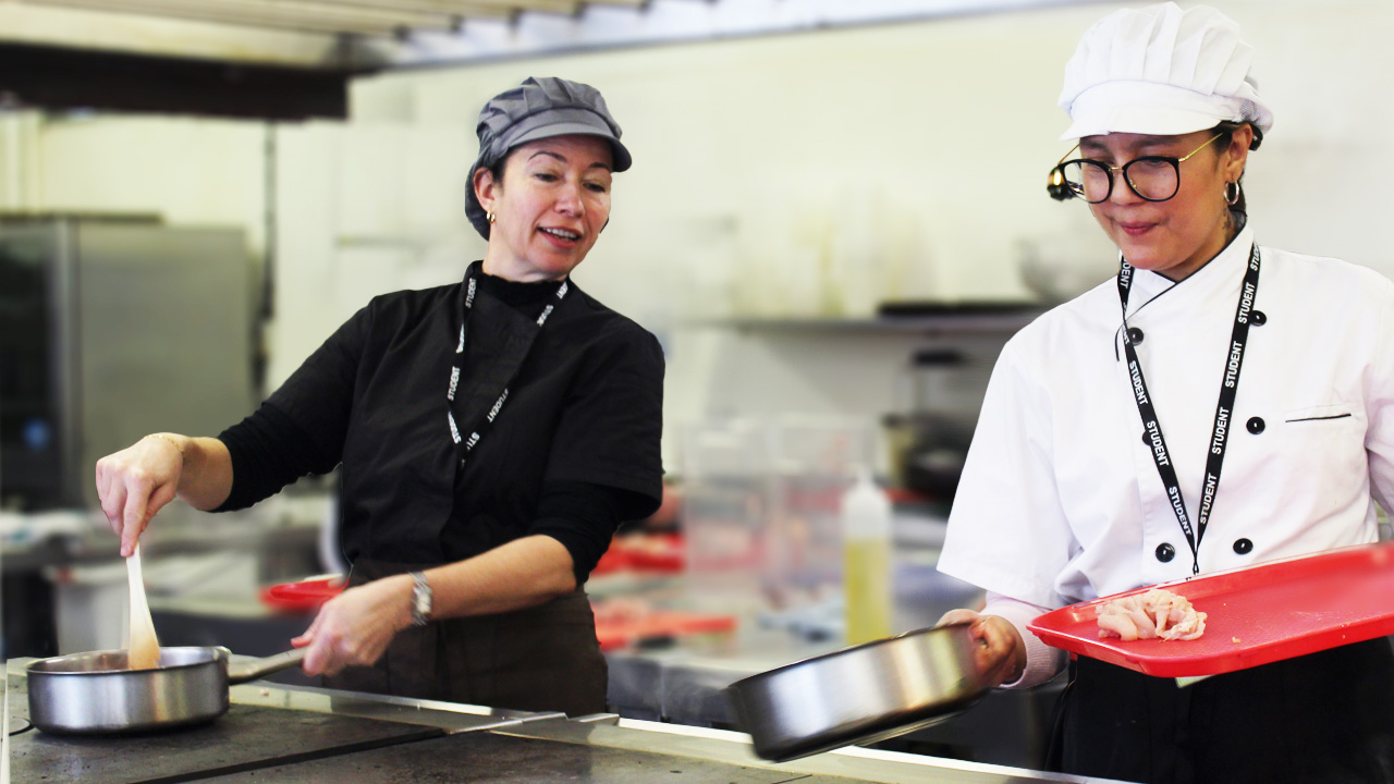 Adult catering students cook chicken dish