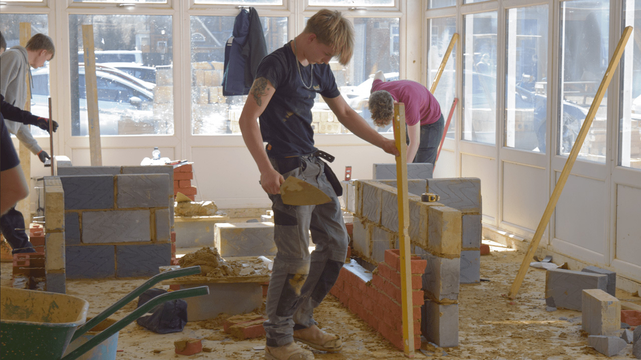 Bricklaying students build walls in construction workshop