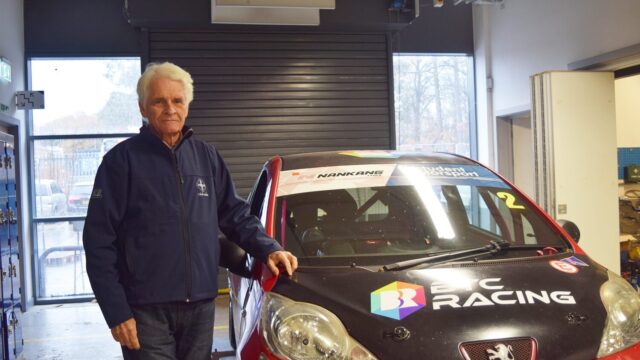 Man standing beside a BRC Racing Peugeot race car with Nankang Tyres and Student Motorsport branding, inside a garage