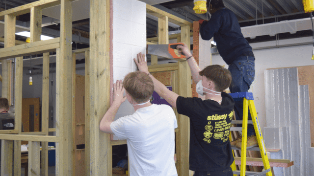 students work in groups of 3 to install insulation in construction competiton